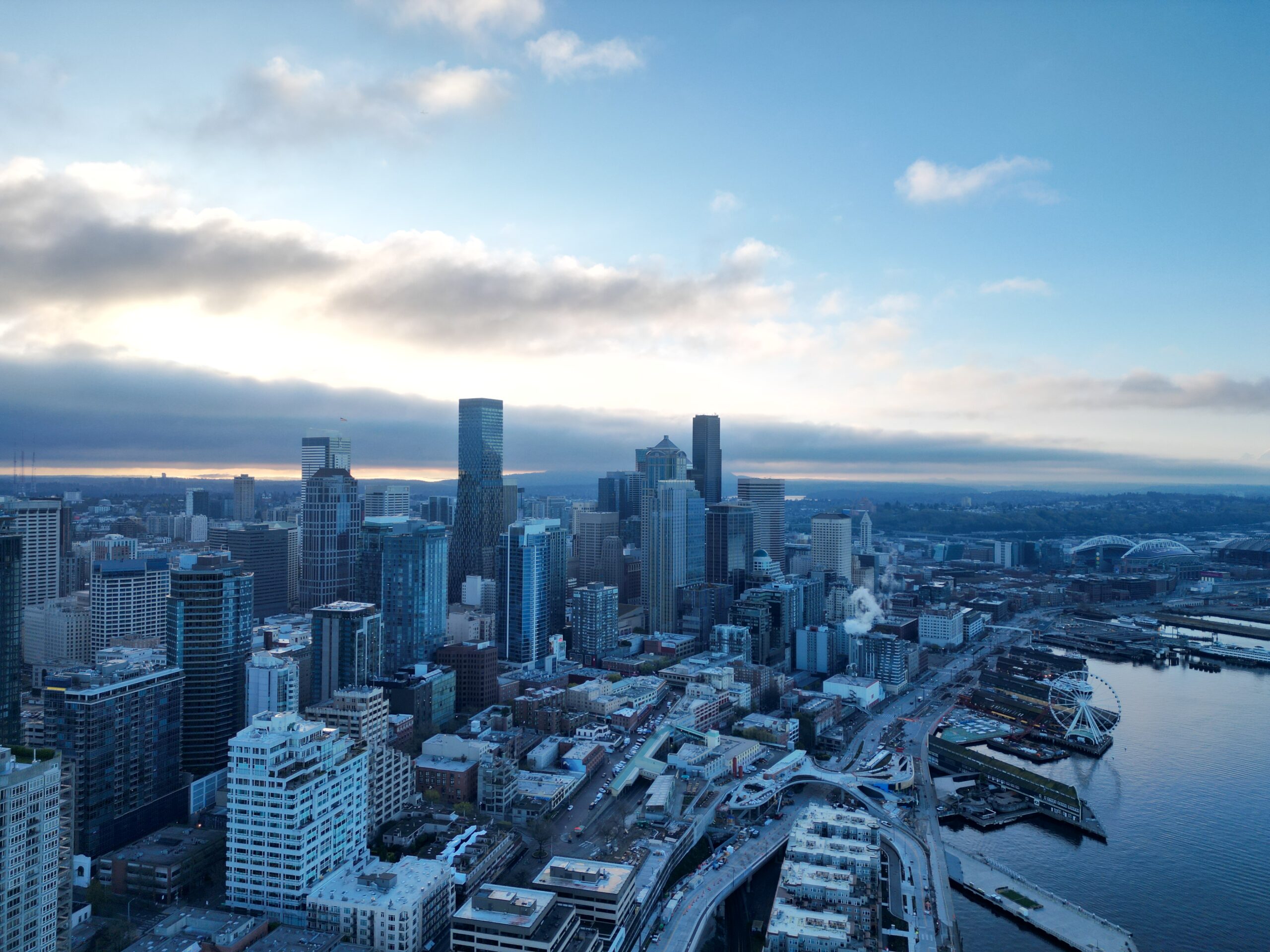 Seattle waterfront with stadiums and Mount Rainier through clouds